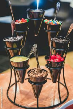 an assortment of desserts are arranged on a stand with spoons and bowls filled with toppings