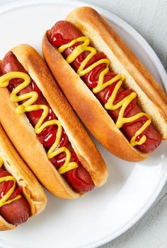 two hotdogs with mustard and ketchup on a plate