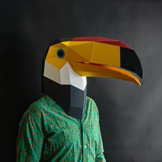 a person wearing a paper bird mask on their head and green shirt with black background