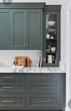 a kitchen with gray cabinets and marble counter tops