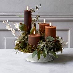 a white plate topped with candles next to flowers and greenery on top of a table