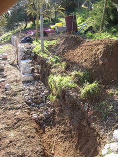 a pile of dirt sitting next to a lush green hillside