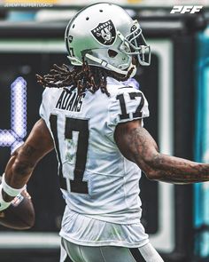 a football player is running with the ball in his hand and has dreadlocks on his head