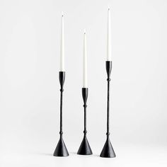 three black candlesticks with one white candle in the middle and two on each side