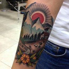 a person with a tattoo on their arm that has an image of mountains and trees