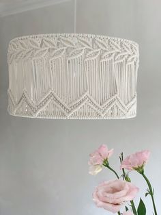 a white chandelier hanging from the ceiling next to pink flowers