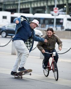 two men are riding their bikes on the sidewalk