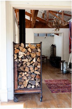 a pile of wood sitting on top of a wooden floor next to a firewood rack