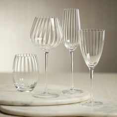 four wine glasses sitting on top of a white marble tray next to eachother