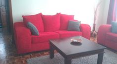 a living room with two red couches and a coffee table