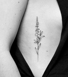 a black and white photo of a woman's stomach with a flower tattoo on it