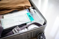 an open suitcase filled with clothing and other items on top of a white flooring