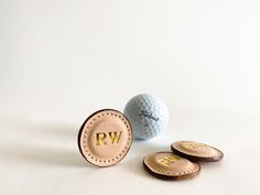 a golf ball and two personalized put - in - place markers on a white background