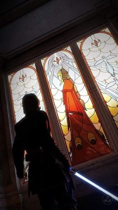 a person standing in front of two stained glass windows with lights coming from them and a light saber