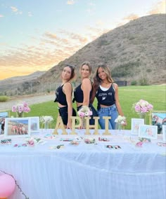 three beautiful young women standing next to a table