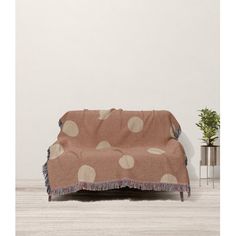 a couch covered in a polka dot blanket next to a potted plant on the floor