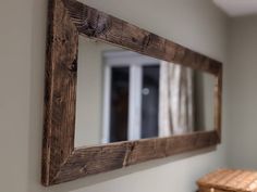 a mirror hanging on the wall next to a wooden bench and stool in a room