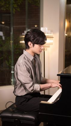 a young man sitting at a piano playing it