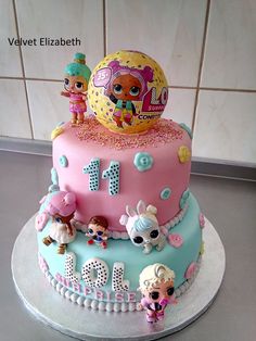 a pink and blue birthday cake with littlest pet shop figures on the top tier