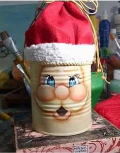 a bucket with a santa claus hat on it sitting on top of a table next to other items