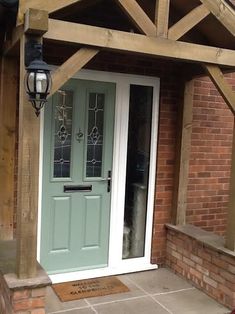 a green front door on a brick building with a lantern hanging from the ceiling and an awning over it