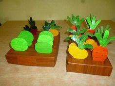 two wooden trays filled with fake vegetables on top of a table next to each other