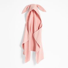 the back of a pink coat hanging on a white wall with an open hoodie over it