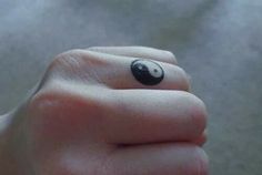 a person's hand with a small black and white ring on their finger that has a panda face painted on it