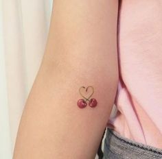 two cherries in the shape of a heart tattoo on the arm