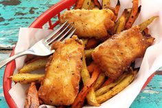 chicken and french fries in a red basket with a fork on the plate next to it