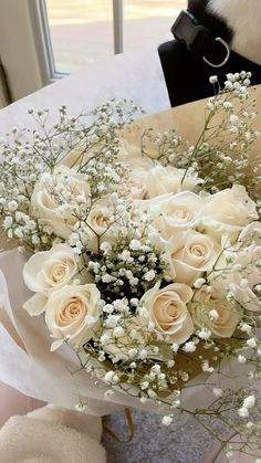 a bouquet of white roses sitting on top of a table