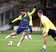 two soccer players in action on the field during a training session, with one running after the ball