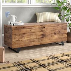 a wooden box sitting on top of a floor next to a plant in a living room