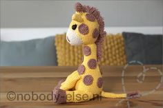 a crocheted giraffe sitting on top of a wooden table