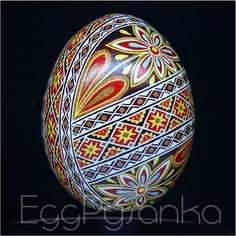 an artistically painted egg with intricate designs on it's side, against a black background