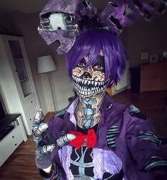 a person with purple hair and makeup is dressed in costume