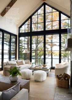 a living room filled with lots of furniture next to large windows and a fire place