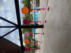 there are many colorful balloons hanging from the ceiling in front of an outdoor swimming pool