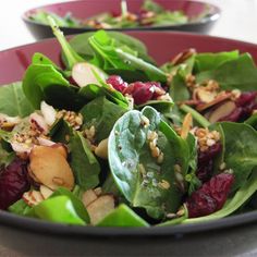 a salad with spinach leaves, cranberries and nuts