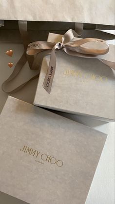 two jimmy choo boxes with ribbons tied around the top and one box has hearts on it