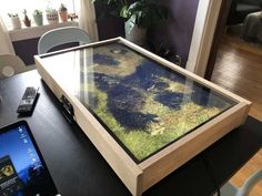 a table with a cell phone on it next to a tablet computer and a plant