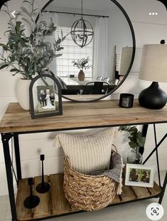 a wooden table topped with a mirror next to a vase filled with flowers and plants