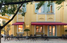 the outside of a restaurant with tables and chairs in front of an open patio area