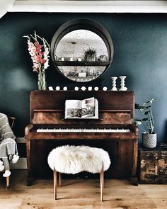 a piano in a living room with a mirror above it