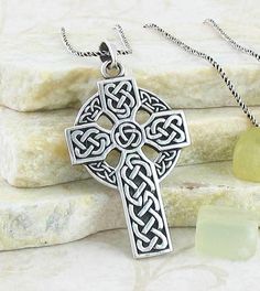 a celtic cross necklace on top of some rocks