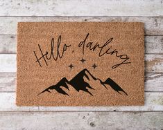 a door mat with the words hello, danking on it and mountains in the background