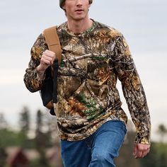 a young man wearing a camouflage shirt and carrying a brown bag walks down the street