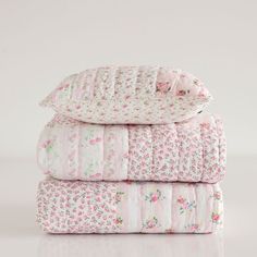 three blankets stacked on top of each other in pink and white floral print, with the covers folded down