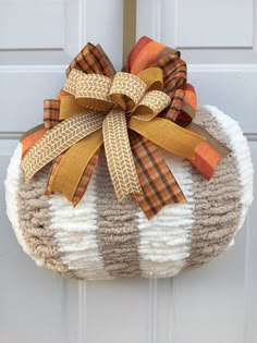 a knitted pumpkin with a bow hanging from it's side on a door