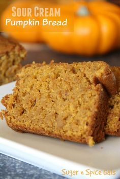 two slices of pumpkin bread on a white plate with oranges in the background and text overlay that reads sour cream pumpkin bread